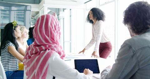 Confident business woman leading diverse team in meeting