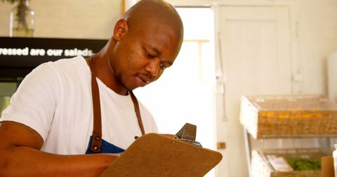 Male staff checking stock in supermarket aisle