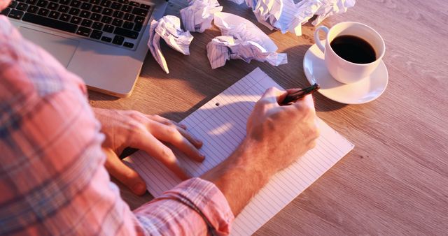 Man Writing on Notebook Next to Laptop and Coffee - Download Free Stock Images Pikwizard.com