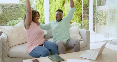 Happy Couple Celebrating Success at Home with Technology
