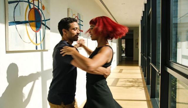 Sunlit couple spinning and twirling in modern corridor dancing close embrace motion
