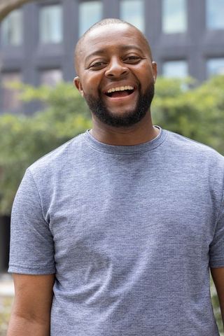 Smiling african man standing in urban courtyard wearing grey heathered t-shirt