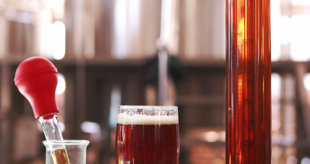 Laboratory equipment and glass of craft beer used for quality control in a brewery. Can be used in articles about craft beer production, brewing process, quality testing in beverages, and the science of brewing.