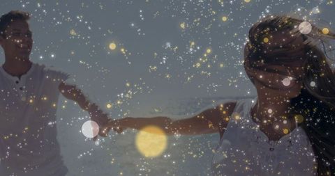 Couple holding hands on sunlit beach with golden bokeh and dreamy backlit romance
