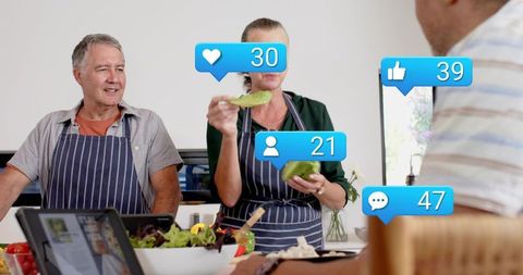 Couple sharing fresh salad ingredients with social media icons in home kitchen