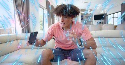 Young man engaging with augmented reality on smartphone in modern sunlit living room