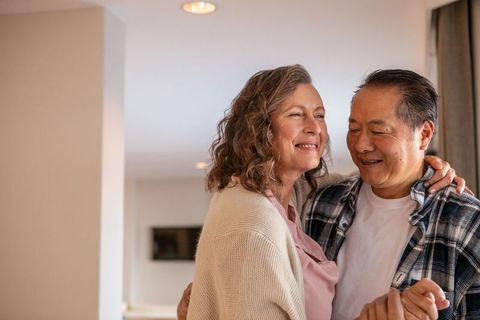 Happy Mature Couple Dancing in Cozy Home Living Room