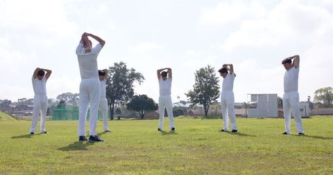 Cricket Team Players Stretching Before Match on Grass Field