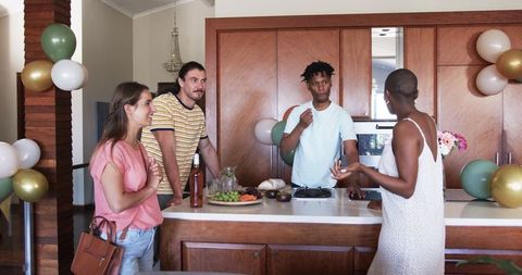 Friends Chatting and Relaxing During Friendly Gathering in Kitchen