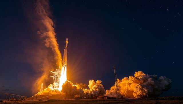 Night rocket launch blasting off from coastal launch pad with fiery plume and starry sky