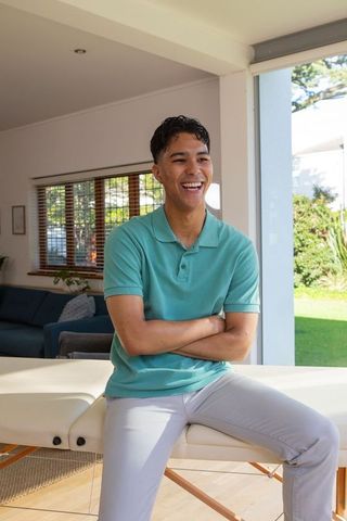 Man Sitting on Massage Table in Sunny Living Room