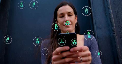 Woman holding smartphone displaying green augmented-reality energy, recycling, tech icons