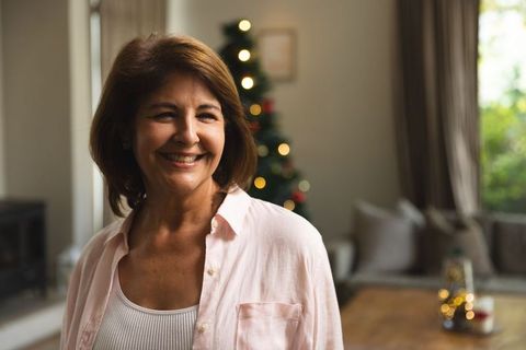 Joyful Woman Smiling in Cozy Living Room with Christmas Decorations