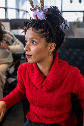 African american traveler wearing led antler headband red sweater waiting in airport terminal
