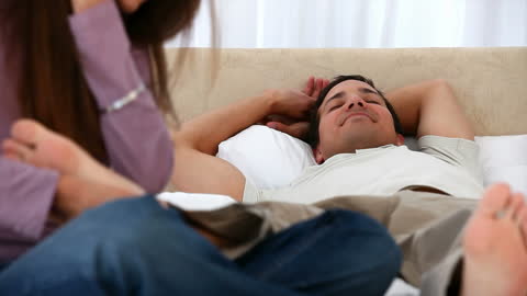 Man Relaxing with Feet Being Massaged by Partner on Bed