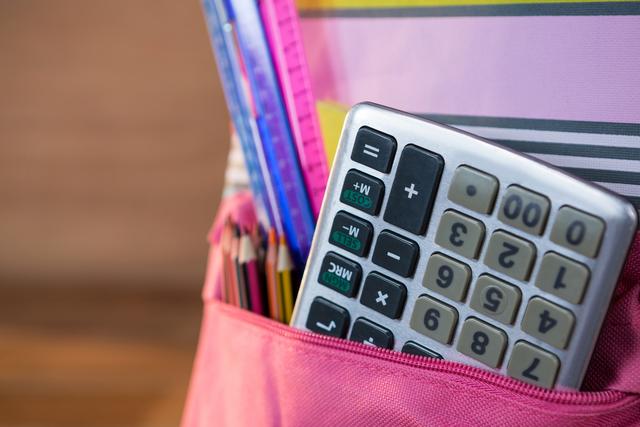This image shows a close-up of a calculator and various school supplies, including pencils and rulers, inside a backpack. Ideal for use in educational materials, back-to-school promotions, and academic websites. It highlights the essentials students need for studying and learning.