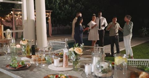 Outdoor evening party with diverse group enjoying conversation and drinks