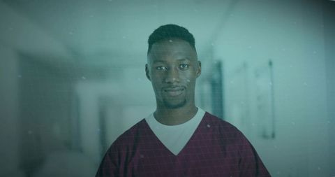 Confident Nurse in Burgundy Scrubs Standing in Hospital Corridor