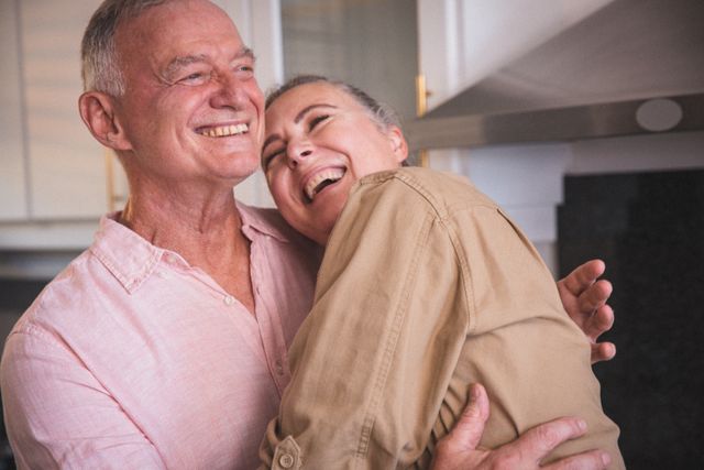 Smiling senior caucasian couple embracing in the kitchen. staying at home in isolation during quarantine lockdown.