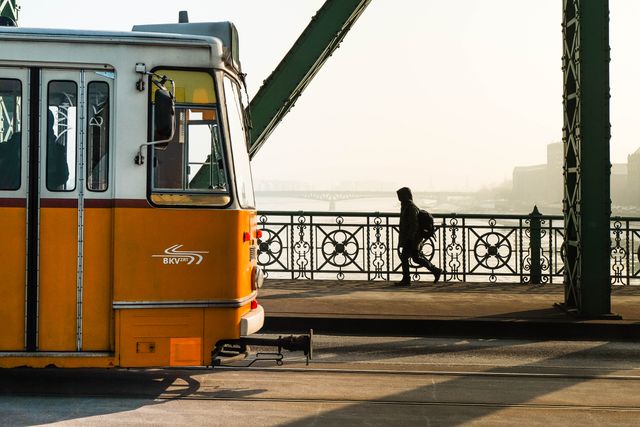 Vintage Tram Crossing Bridge at Sunset with Silhouetted Pedestrian - Download Free Stock Images Pikwizard.com