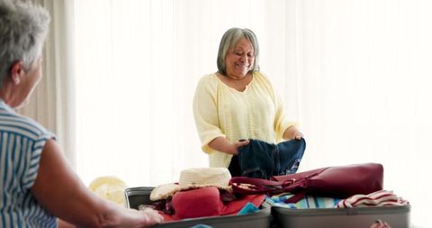 Senior lesbian couple packing for travel in bedroom