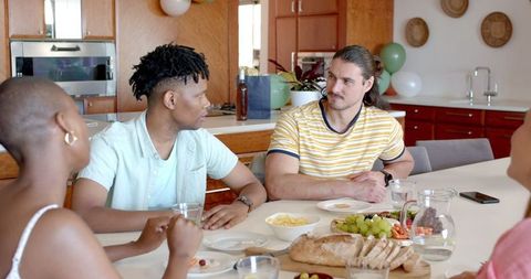 Friends Enjoying Casual Conversation and Snacks at Dining Table