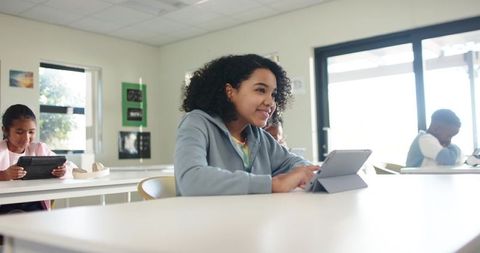 Sunlit classroom students using tablets African American girl engaging in digital learning