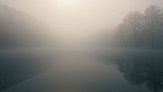Serene Mist-Covered Lake with Soft Tree Reflections