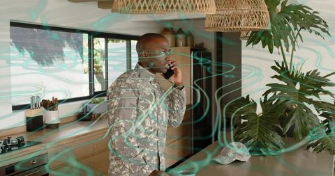 Man calling on smartphone while wearing grey camouflage jacket in modern kitchen interior