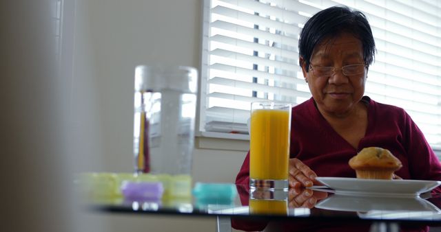 Senior Woman Having Breakfast with Orange Juice and Muffin Near Window - Download Free Stock Images Pikwizard.com