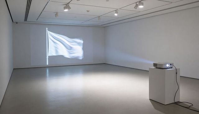 Waving white flag projection in minimalist gallery with digital projector and pedestal