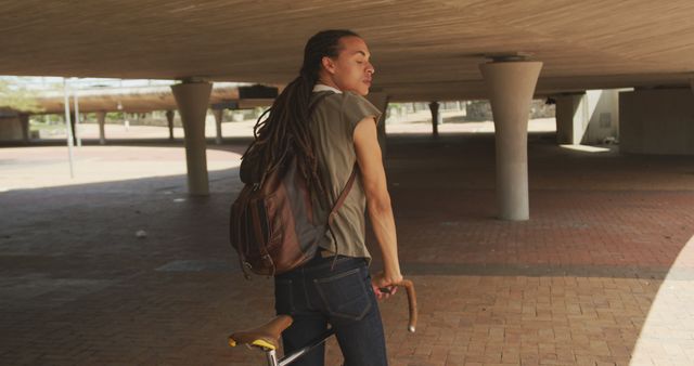 Young man with dreadlocks biking in urban environment - Download Free Stock Images Pikwizard.com