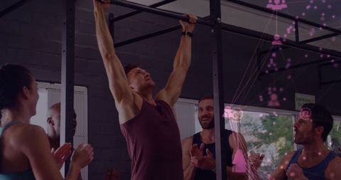 Man performing pull-up on metal rig while teammates cheer during group workout boosting motivation