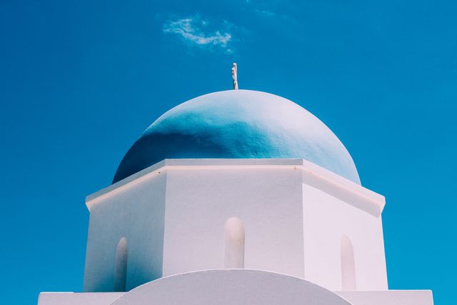 This image features a traditional white and blue domed Greek church, a hallmark of Mediterranean architecture, particularly found in Santorini. Ideal for travel blogs, tourism promotions, cultural articles, religious publications, and design inspiration. The clean and vibrant composition makes it perfect for showcasing the beauty of Greek landmarks and promoting Mediterranean destinations.