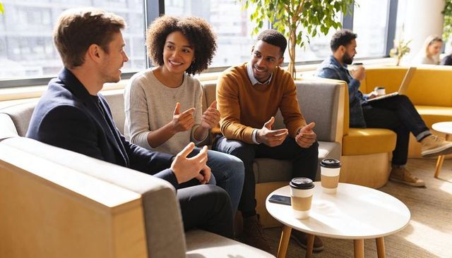 Casual office team collaborating over coffee in modern lounge for brainstorming