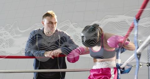 Boxing coach coaching female boxer during corner break with pink gloves and headgear