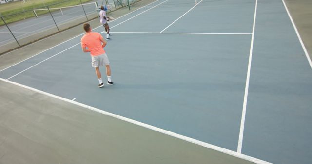 Two Men Playing Tennis on Outdoor Court at Sunset - Download Free Stock Images Pikwizard.com