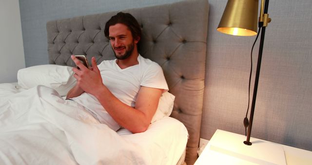 Young Man Relaxing in Bed Texting on Smartphone at Home - Download Free Stock Images Pikwizard.com