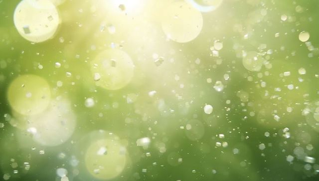Drifting sunlit particles and bokeh orbs creating sparkling green nature light background