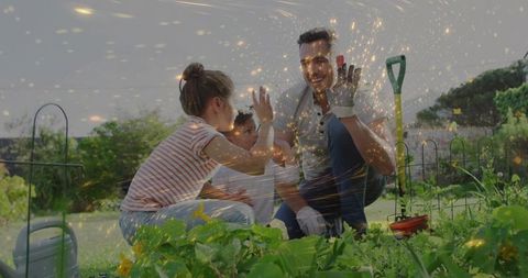 Happy father and children high-fiving in vegetable garden