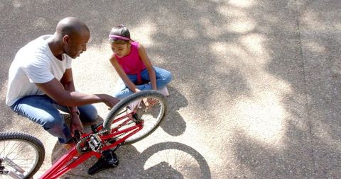 Father Teaching Daughter Bicycle Repair Outdoors