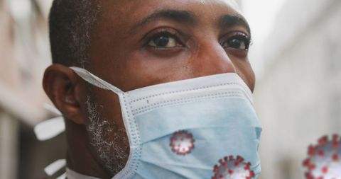 Portrait of man wearing face mask with covid-19 virus overlay