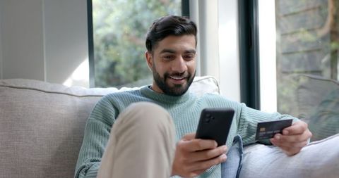 Smiling Man Shopping Online with Smartphone and Credit Card on Couch - Download Free Stock Images Pikwizard.com