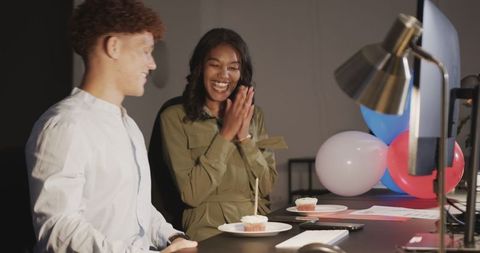 Office celebration with cupcakes, diverse coworkers enjoying party