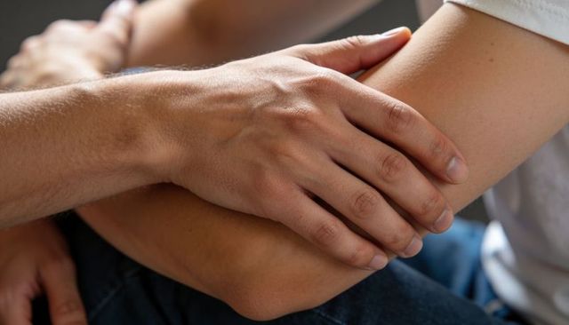 Comforting hand holding forearm closeup conveying support, empathy, intimacy and care