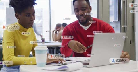 Black professionals collaborating over laptop in modern coworking space with data overlays