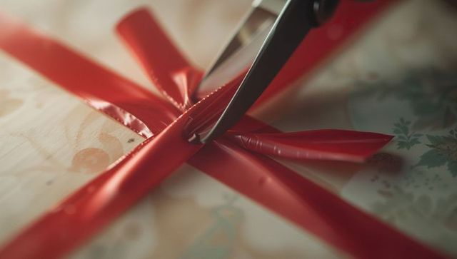 Close-up of scissors cutting red ribbon on gift box