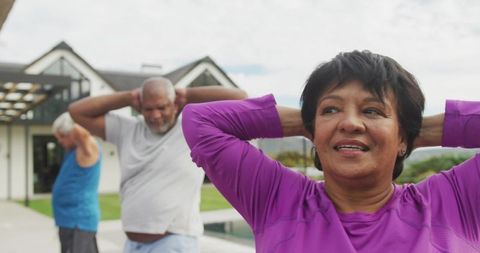 Senior woman stretching poolside with friends during outdoor morning exercise