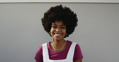 smiling woman with afro hair standing against urban wall - Download Free Stock Images Pikwizard.com