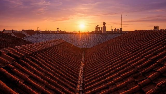 Golden sunset over converging red clay rooftops, urban silhouette, slate ridge, warm light
